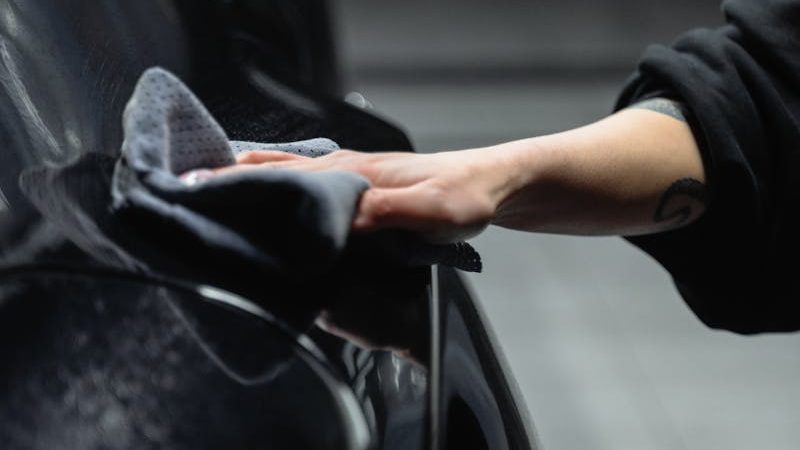 A Person Wiping a Car with a Cleaning Cloth